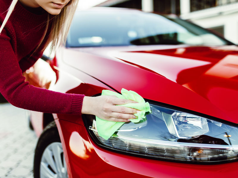 a women cleaning her car headlight