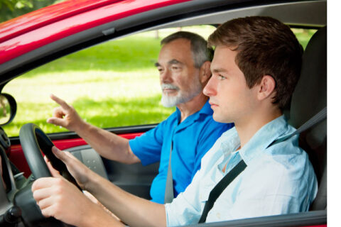 man teaching a teeanger to drive the car