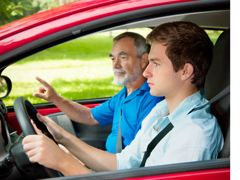 old man teaching how to drive to teenager