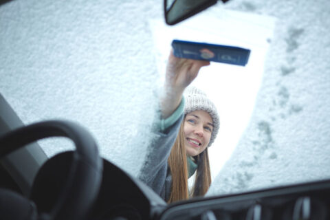 a girl wiping the car windshield covered with snow