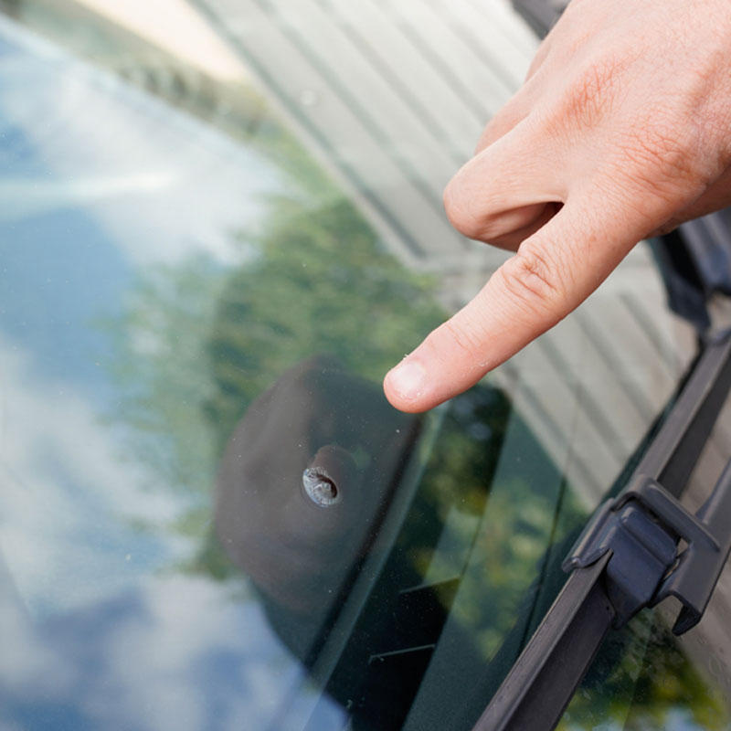 finger pointing at chip in windshield