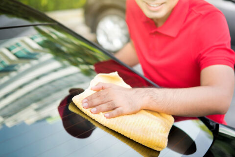 man wearing a red tshirt wiping the car windsheild